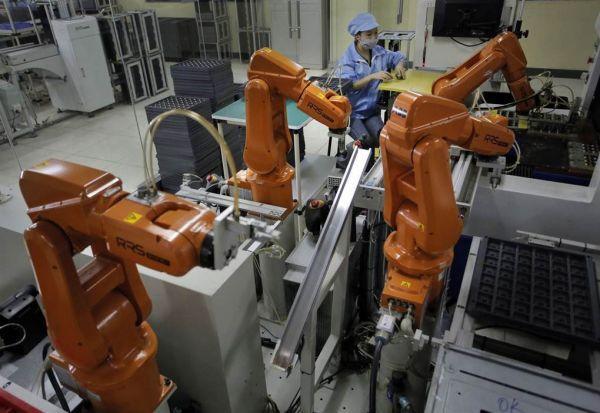 在深圳雷柏科技公司的工厂里,操作员正使用机械臂组装电脑配件.
